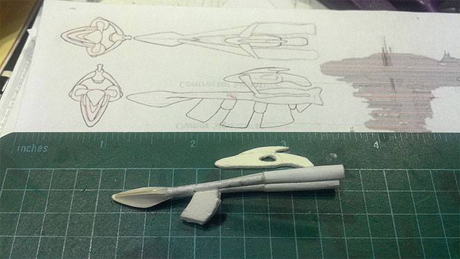 This ship in progress is about 2.5 inches long and so far the bow, rear prongs, and one of the lower ribs are complete. The ship is shown next to a small sketch that has been sized to help determine the model's scale.